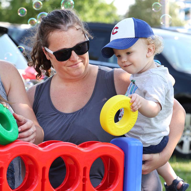 Carrie Freeman and her son Jackson, 1, from Sycamore, play a game at the Family Service Agency booth during the Family Fun Fest Thursday, July 20, 2023, at Hopkins Park in DeKalb.