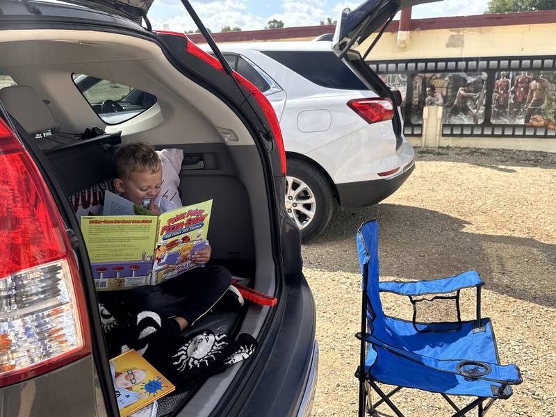 Austin Oliver of Johnsburg enjoys some cotton candy while taking in one of his favorite books before the movies start at the McHenry Outdoor Theater. Representatives from 11 area libraries will offer card sign-ups, giveaways and more Sept. 19 at the theater. Touch-a-Truck takes place Sept. 20. Both events are part of owner Scott Dehn’s 25th anniversary celebration.