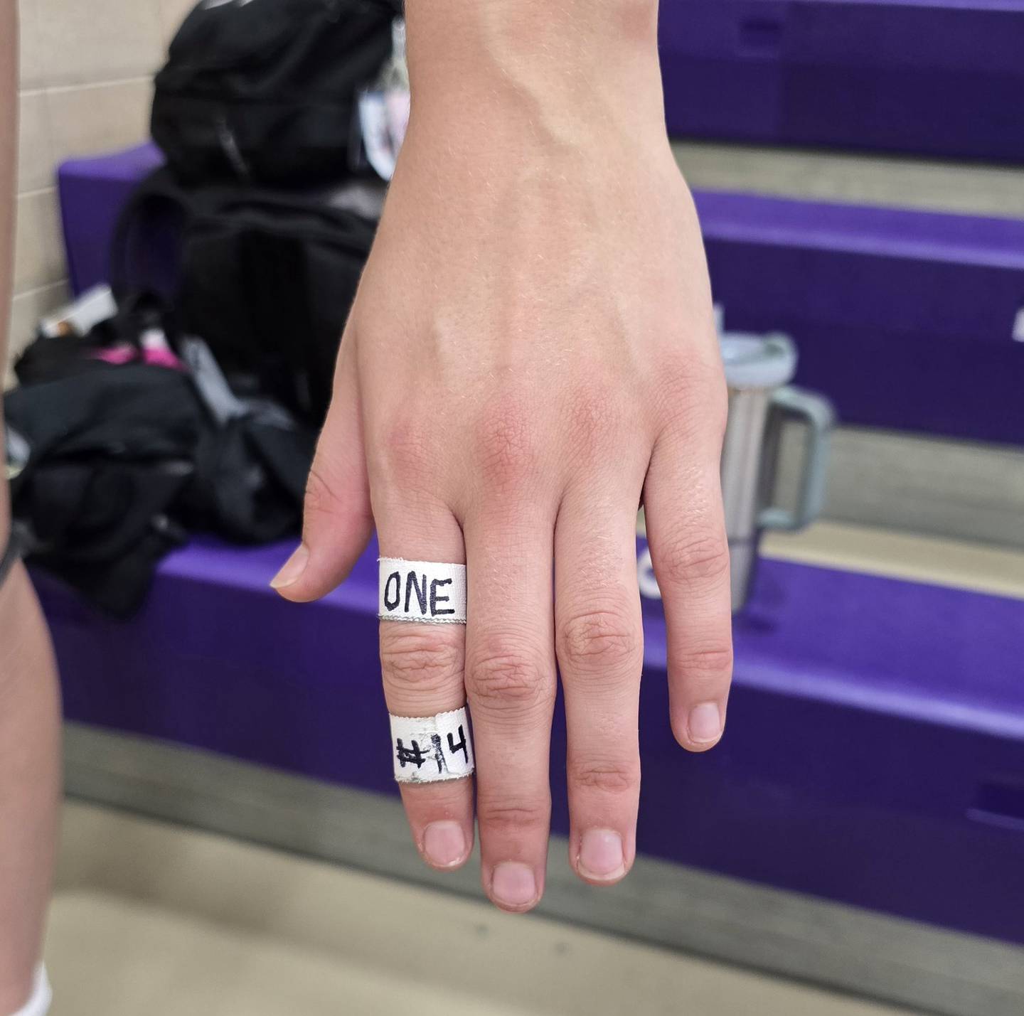 Dixon's Leah Carlson shows her taped finger with the word "one" written on it. It is a motto she and the rest of the volleyball team have emphasized this season.