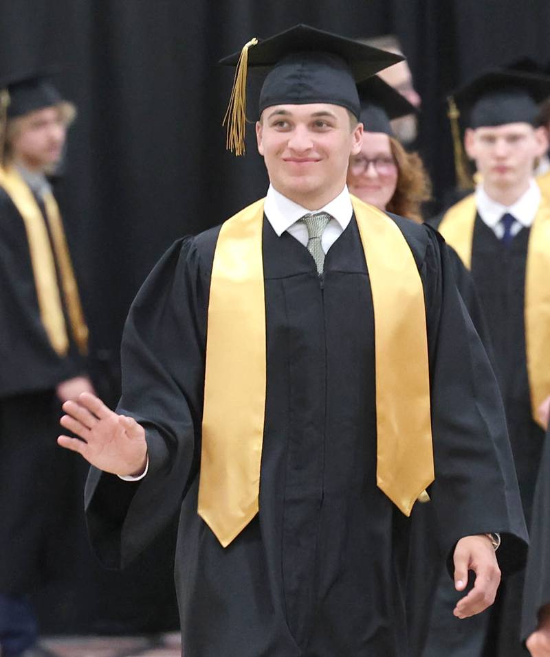 Gus Cambier waves to friends and family as he heads to his seat during commencement ceremonies Sunday, May 28, 2023, at Sycamore High School.