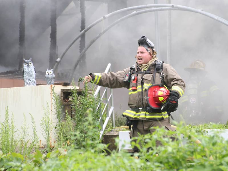 La Salle firefighter Hunter Thurman motions to Ameren crews to cut power during a fully-engulfed structure fire in the 500 block of North 2782nd Road on Monday, July 21, 2025 in La Salle. FIre departments from Utica, Wallace, Naplate, Spring Valley, Mendota, Troy Grove, La Salle, Peru, Oglesby and Tonica responded to the scene. Fire crews were dispatched at 9:45 a.m. La Salle Police and La Salle County Sheriff were also on the scene.