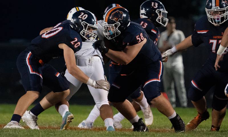Oswego’s Dylan King (20) and Hayden Stroud (58) open a hole against Neuqua Valley's Justen Crawford (55) during a football game at Oswego High School on Friday, Aug 26, 2022.
