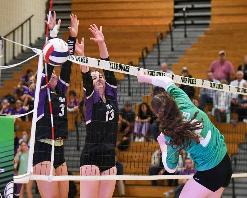 Downers Grove North's Sarah Rutkowski (3) and teammate Nora Benjamins (13) block the ball from York's Eileen Carroll (2) during the game on Tuesday Oct. 22, 2024, held at York High School in Elmhurst.