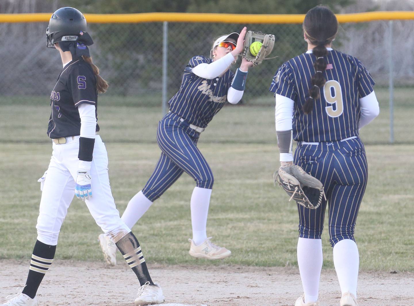 Marquette's Hunter Hopkins (center) makes a catch on the run as Serena's Jenna Setchell looks on while standing on second base on Wednesday, March 26, 2025 at Serena High School.