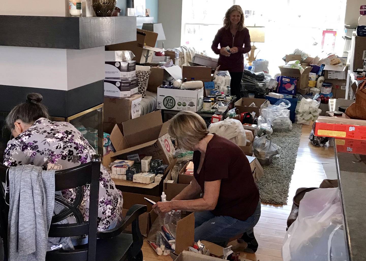 Community volunteers Tonya Traverso (left) of Oswego, Roxanne Mairs-Hawrylewicz (center front) and Vickie Drendel (back) of Naperville working in the home of Rene Koehler to sort and pack donations from the community for Ukrainian refugees.