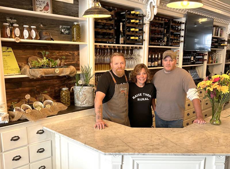 Dan Marquis (left) poses with his mother, Pat Marquis (center), and brother, Tim Marquis (right), behind the wine bar at Wild Ginger Bistro. Next to them, there is a space where customers will be able to purchase fresh produce and other local products. Dan said they used barnwood from their barn and gathered family and community memorabilia to create a special, inviting ambiance.