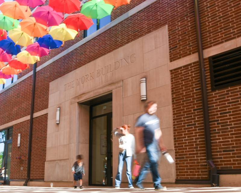 Community members walk underneath hanging umbrellas at Schiller Court on Saturday May 31, 2025, during the Elmhurst Summer Kick Off Party held at City Centre Fountain Plaza in Elmhurst.