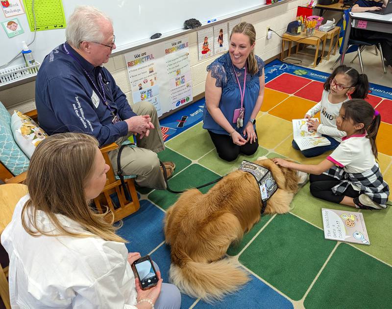 Second-grade students in teacher Melissa Lundy’s Troy Heritage Trail Elementary School classroom read to comfort dog Nigel, with his handler U.S. Army veteran James Morrison and LCC K-9 Military Ministry dog program representative Marta Rees.