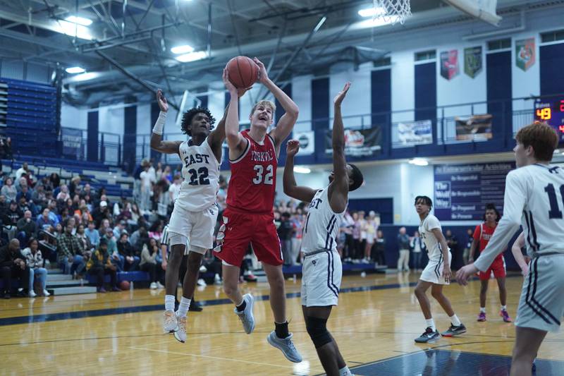 Yorkville's Jason Jakstys (32) shoots the ball in the post against Oswego East's Jehvion Starwood (22) and Andrew Wiggins (1) during a basketball game at Oswego East High School on Friday, Dec 8, 2023.