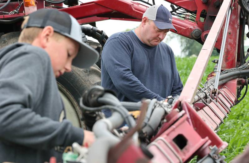 Farmer Mike Schweitzer and his son Eli, 12, change the sprayer nozzles on a tractor in one of his fields Friday, June 16, 2023, on his farm in Malta.