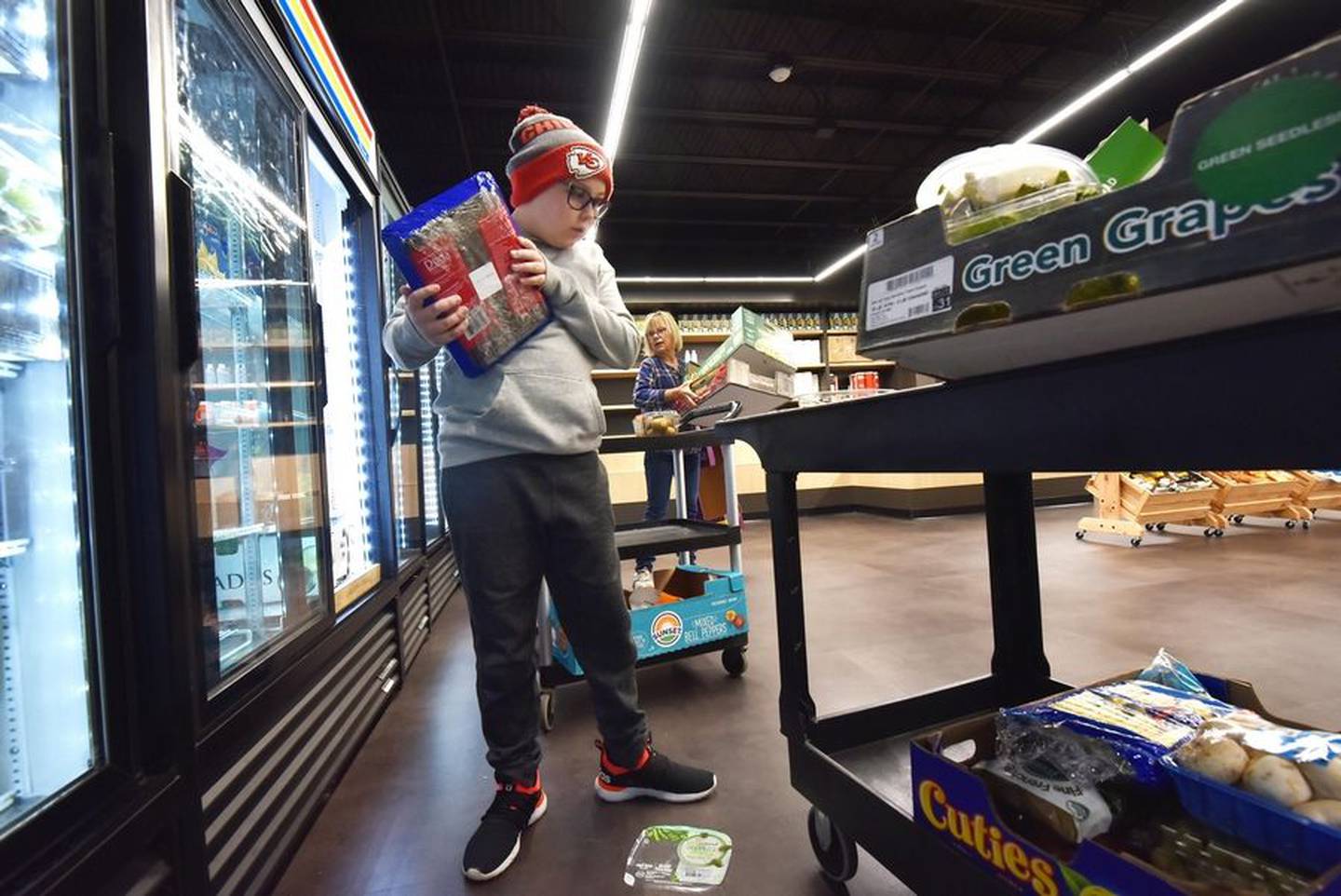 Volunteer Greyson Halley, 10, stocks a refrigerator at the Shepherd's Heart Food Pantry in Geneva. More people are relying on food pantries in the suburbs as grocery store prices increase.