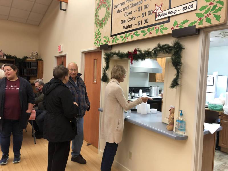 Attendees of the German Christkindlmarket in Princeton line up to taste authentic German food, including bratwurst and sauerkraut on Saturday, Nov. 19, 2022 at Open Prairie United Church of Christ.
