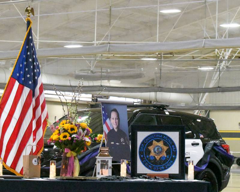 Items are displayed on a table during a memorial vigil to mark one year since the late sheriff's deputy Christina Musil, 35, was killed in the line of duty in a rear-end car crash in Waterman while on patrol on March 28, 2024. The vigil was held at the Sycamore High School Field House on Saturday, March 29, 2025.