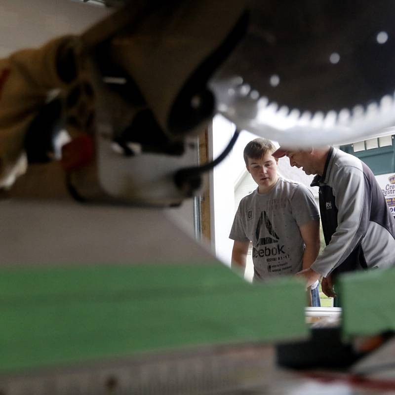 Erich Parpart teaches junior Aaron Hugger how to cut a stair skirt board as students in the Woodstock Building Trades Program put the finishing touches on a home they are building in Woodstock on Monday, May 8, 2023. This will be the program's 43rd completed home since it began in 1972.