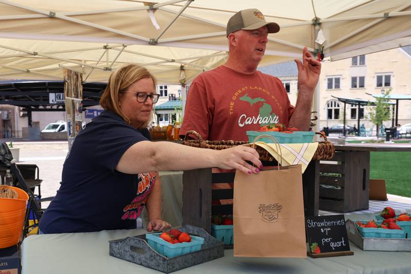 Home Run Harvest owners Lisa and Steve Otto help a customer at the new city square for the farmers market on Friday, May 22, 2026 in Joliet.