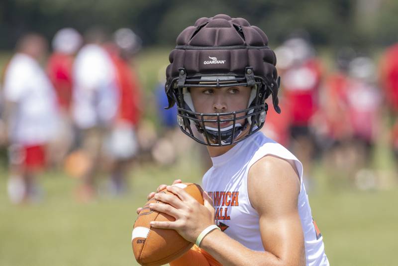 Sandwich quarterback Brady Behringer looks for a receiver downfield during a multiple high school practice football meet at Princeton High School on July 20, 2024.