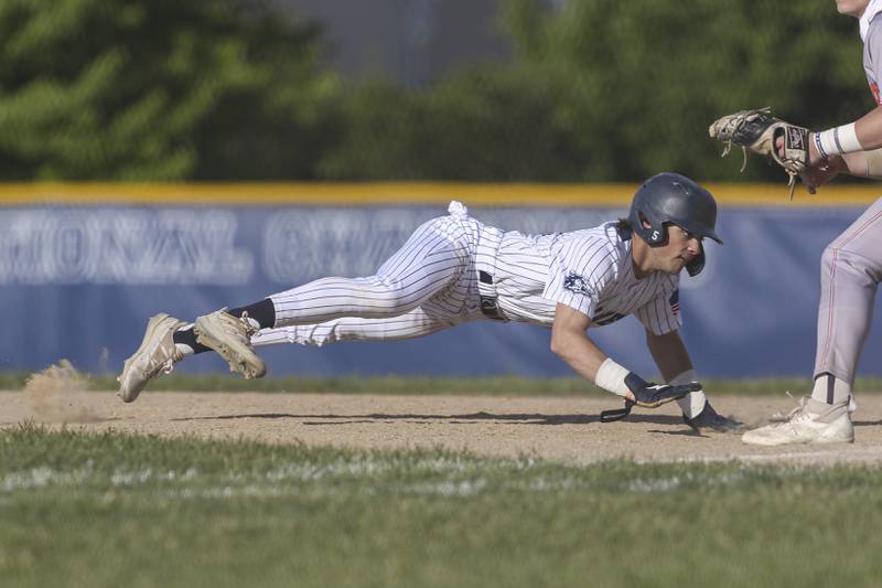 Oswego East's Niko Villacci (8) dives back to first during a pickoff attempt during baseball game between Oswego East at Oswego. Monday, May 19, 2025 in Oswego.