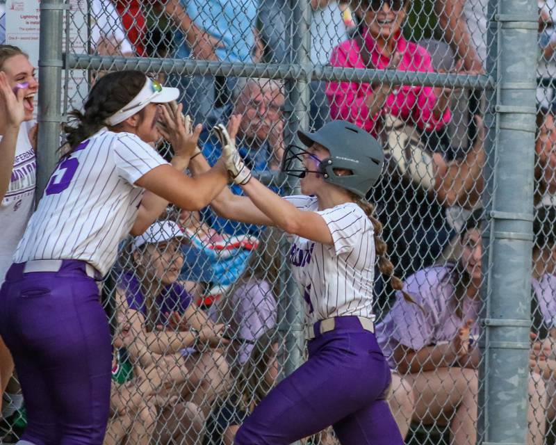 Downers Grove North's Samantha Lehnherr (11) is congratulated by teammates after scoring during varsity softball game between Downers Grove South at Downers Grove North.  May 11, 2023.