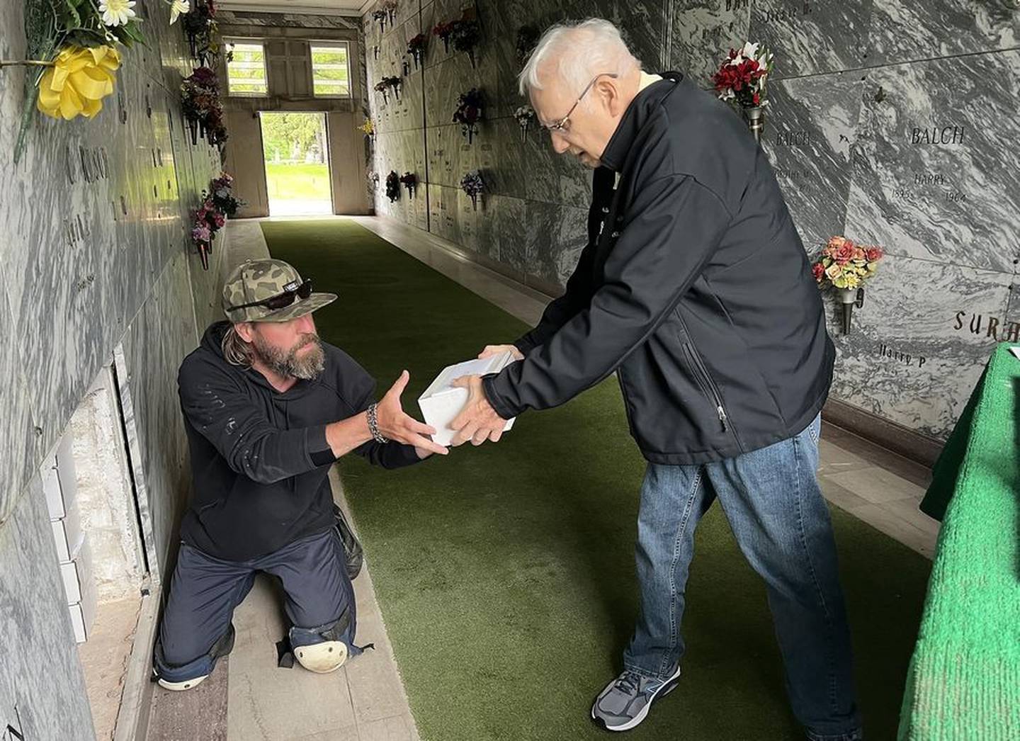 Brooks Ronzheimer, left, St. Charles Township cemetery superintendent, and Ron Johnson, supervisor of St. Charles Township, put remains of unclaimed ashes of people into an empty vault at North Cemetery in St. Charles on May 27, 2022, after a memorial service arranged by the Kane County coroner. The remains of 35 people were entombed.