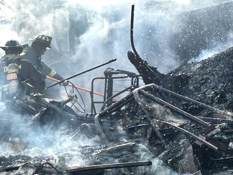 Firefighters look for hot spots following a garage fire at 6727 W. Henry Road, southeast of Polo, on Wednesday, March 26, 2025. Several departments responded to the fire at the rural residence.