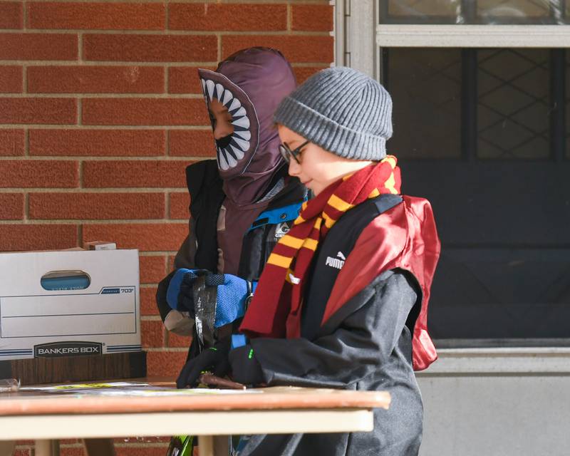 (From left) Logan Horton, 10, and Brantley Robinson, 9, pick out candy while trick-or-treating for Halloween on Thursday, Oct. 31, 2024, in DeKalb.