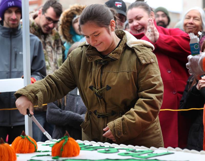 Rayven Rosas, this year’s theme winner, makes the first cut of the cake Wednesday, Oct. 22, 2025, during opening day of the Sycamore Pumpkin Festival.