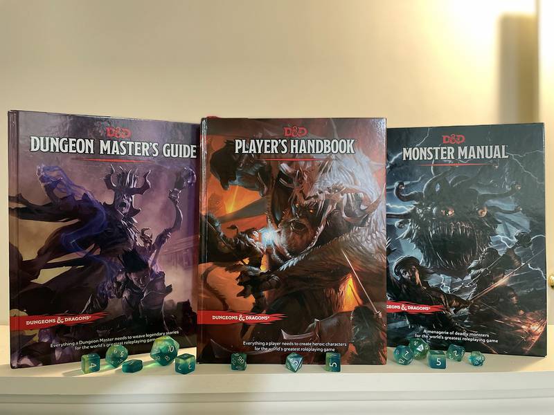 The three main Dungeons & Dragons sourcebooks with a set of tabletop roleplaying dice in front of them.