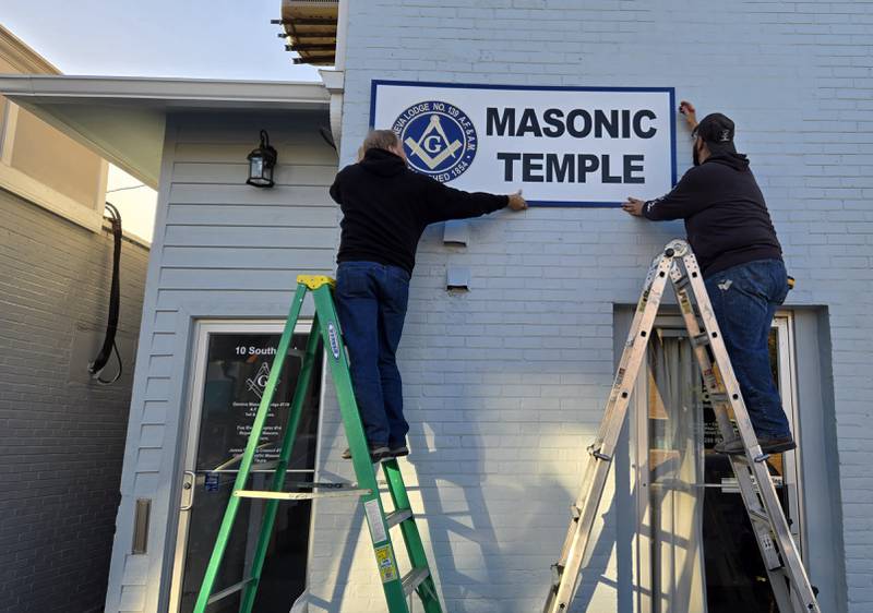 Members of the Geneva Masonic Lodge No. 139 Eric Johnson (left) and Jason Rosas hang a new sign in preparation for a Geneva Chamber of Commerce ribbon cutting Friday, Oct. 25th in honor of the Lodge's 170th anniversary.