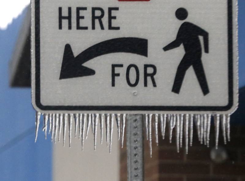Ice hangs from a pedestrian crossing sign in the parking lot of the Walmart in Woodstock on Wednesday, Feb. 22, 2023, as a winter storm that produced rain, sleet, freezing rain, and ice moved through McHenry County.