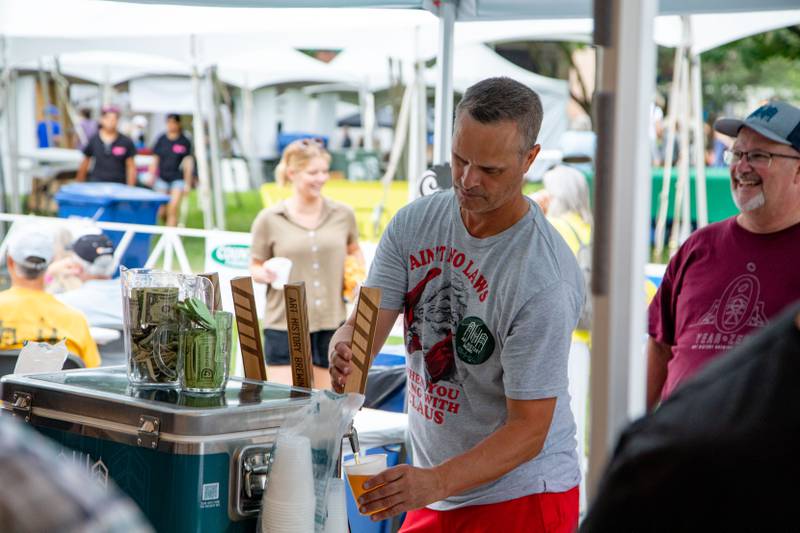 Gary Spratt of Geneva pours beer from a tap in the Art History Brewing tent at Swedish Days on Saturday, June 25, 2022.