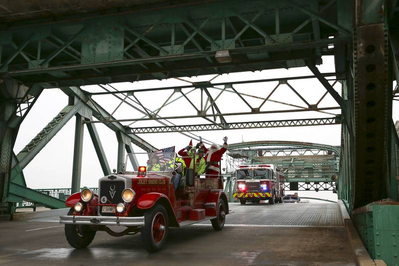 Santa Claus and friends cross the bridge over the Des Plaines River on Saturday, Dec. 19, 2020, at Plainfield South High School in Plainfield, Ill. Local families wait for a glimpse of Santa Claus during the Santa Send-off event. With the help of Joliet officials, Santa traveled through downtown Joliet, concluding his trip at Plainfield South.