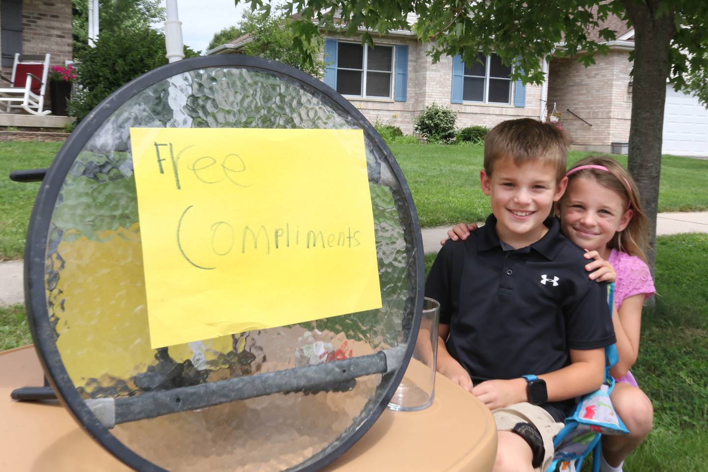 Ethan Wargo, 9, and his twin sister, Claire, at the free compliments stand in front of their house Thursday, July 24, 2025, in Sycamore. Ethan offers free compliments to anyone who stops by, but he said tips are accepted and appreciated.
