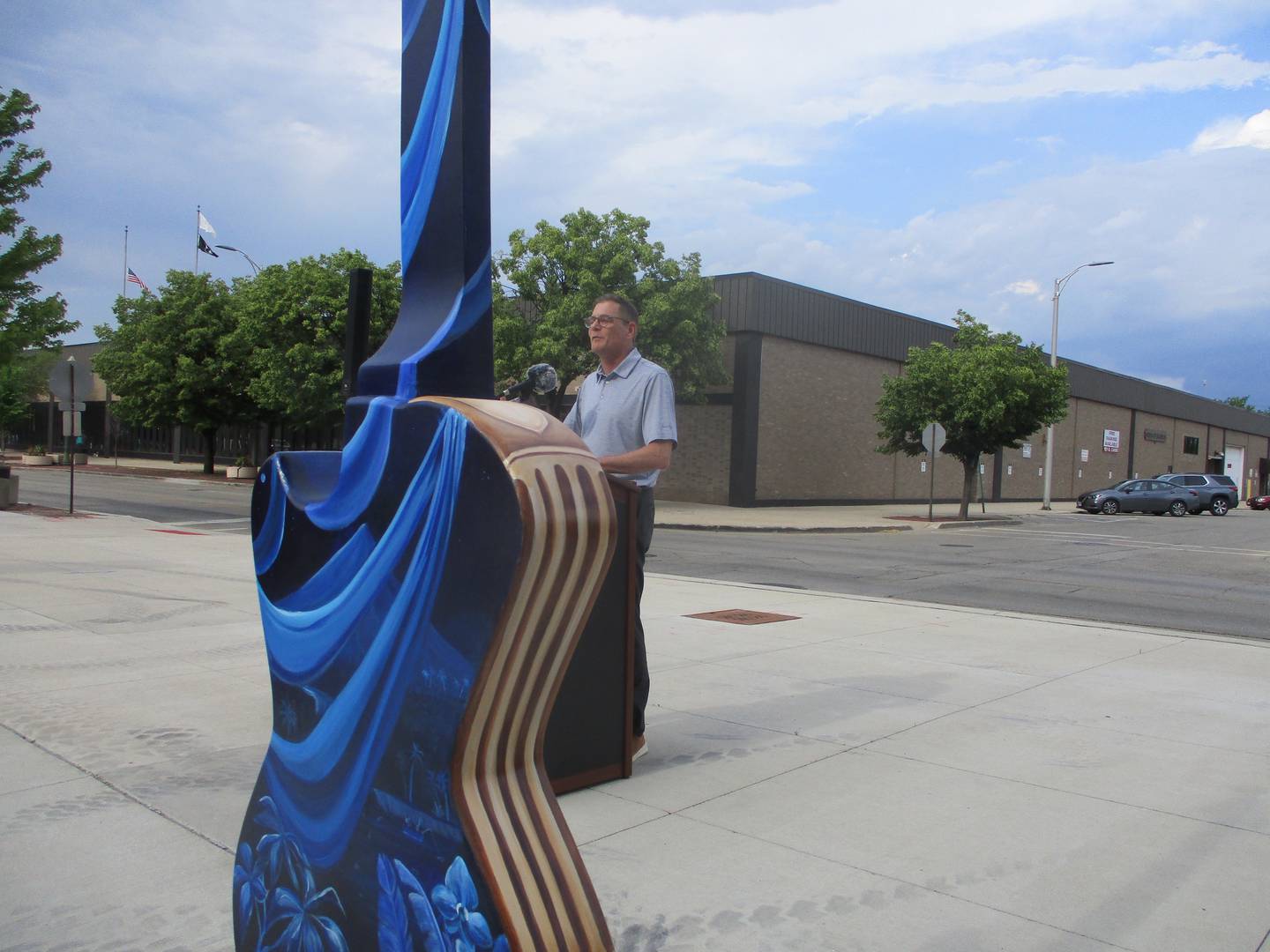 Rod Tonelli, chairman of the Joliet City Center Partnership, speaks with a painted guitar in the foreground on Thursday during an opening ceremony for the "Ready to Rock" street art project in downtown Joliet, June 1, 2023.