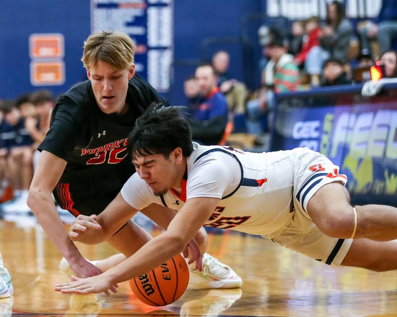 Oswego's Michael Delgado (20) dives for a loose ball during their basketball game between Yorkville at Oswego, Tuesday Dec 10, 2024 in Oswego.