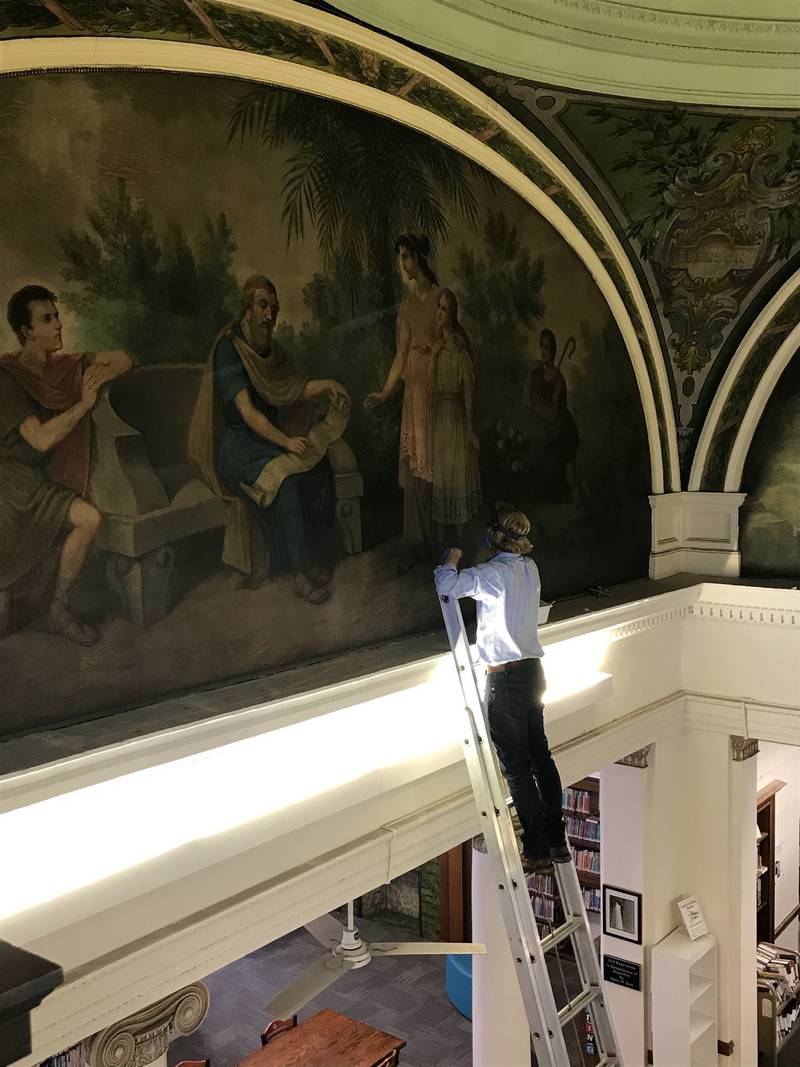 A representative from Parma Conservation examines one of the murals beneath the Streator Public Library rotunda.