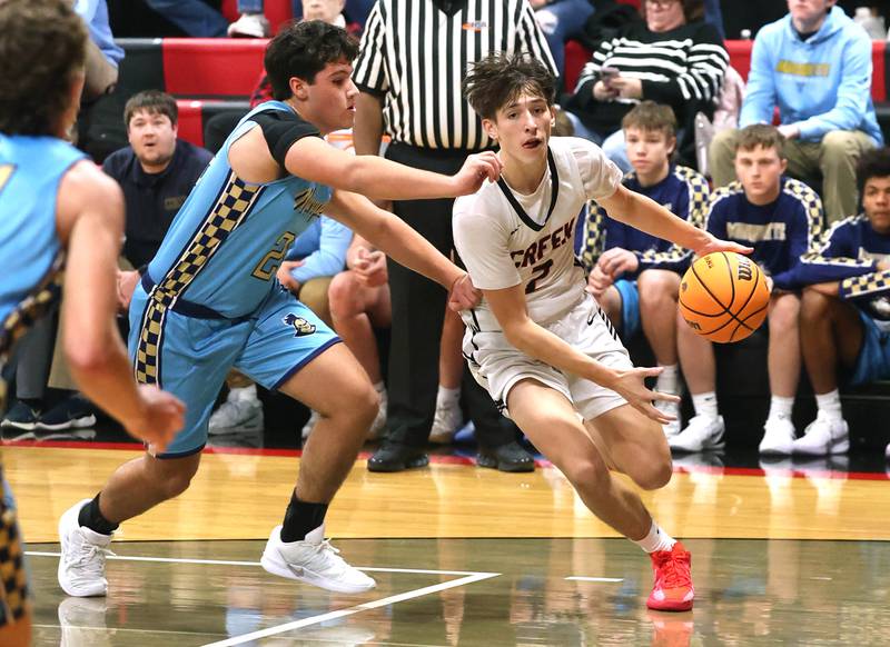 Indian Creek's Jason Brewer goes by Marquette’s Matt Graham Monday, Dec. 9, 2025, during their game at Indian Creek High School in Shabbona.