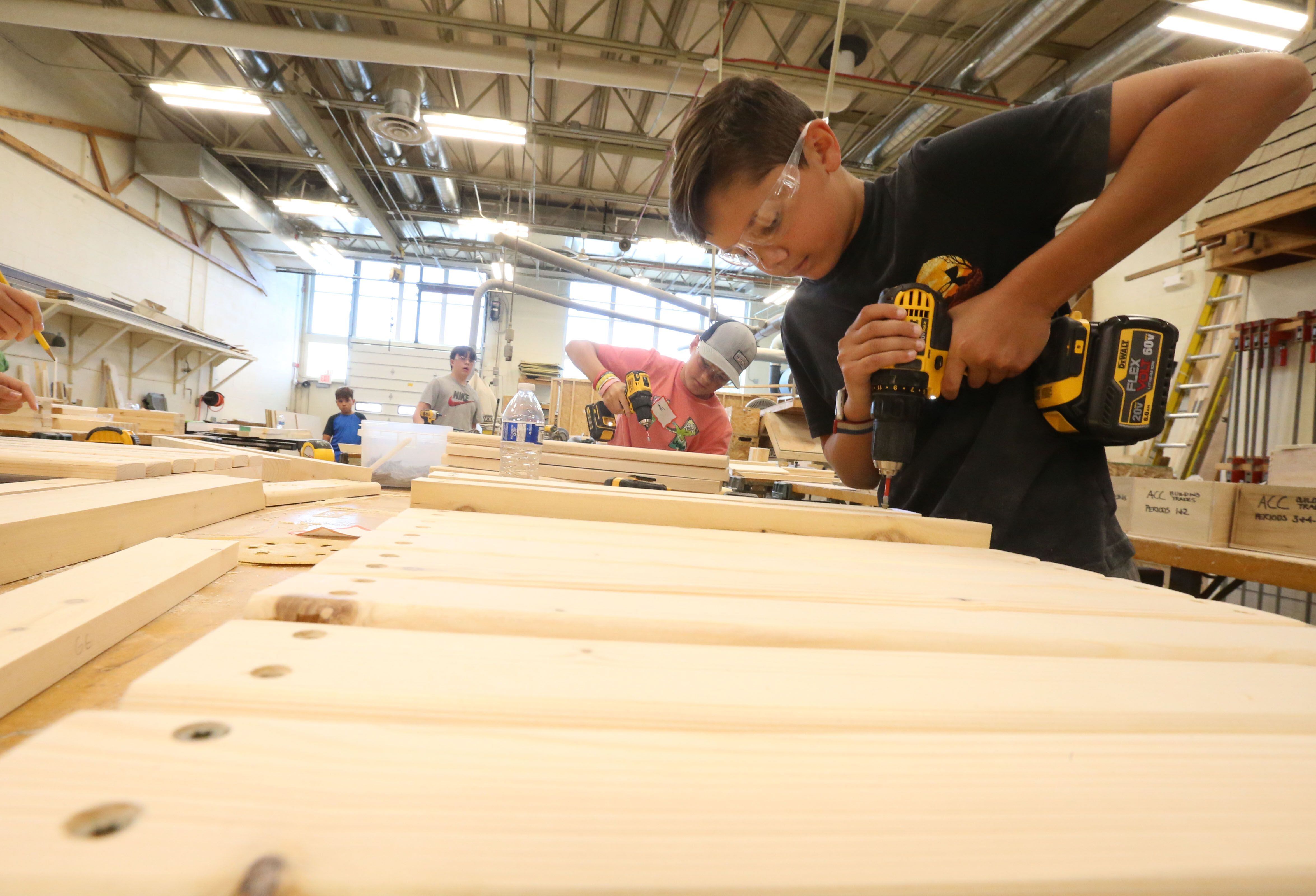 Students Cale Full and Geno Agrubright use drills to screw into boards while making a Adirondack chair during the Area Career Center's Summer Hands-On Showcase on Thursday, June 8, 2023, at La Salle-Peru High School.