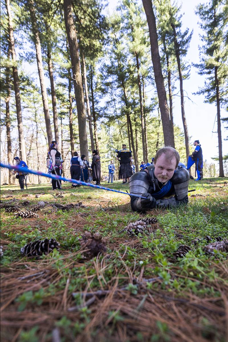 Nicholas Workman of Morrison drags himself across a rope to simulate crossing a chasm Saturday, April 13, 2024 during game play. CER LARP play consists of three aspects of play - storytelling, character development, and combat.