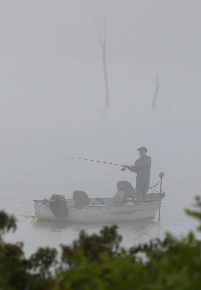 A fisherman tries his luck on a foggy morning Monday, July 22, 2024, in the lake Shabbona Lake State Recreation Area in Shabbona Township.