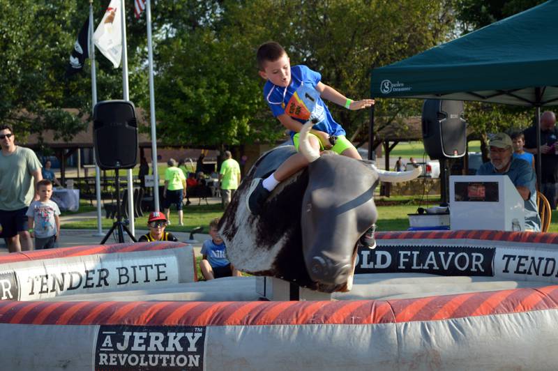 Charlie Slick, 8, of Forreston, tries to stay astride a mechanical bull on Friday, Aug. 2, 2024, during Forreston Sauerkraut Days.