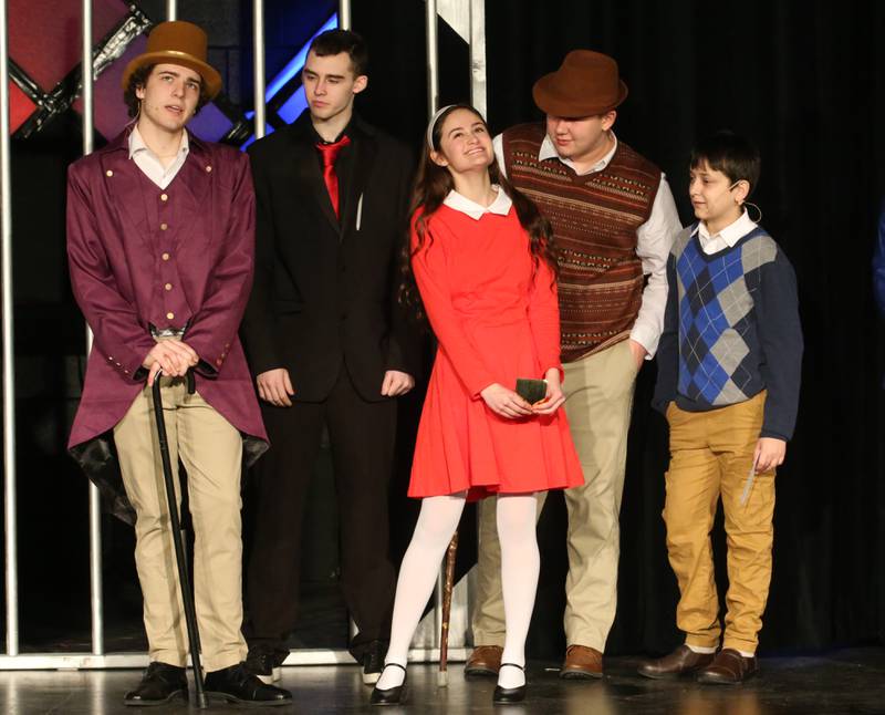 Willy Wonka, played by Mavrick Holocker, Mr. Salt, played by Cole Vipond, Veruca Salt, played by Maddy Wasilewski, Grandpa Joe, played by Eric Vipond and Charlie and Charlie Bucket, played by Seth Sandberg act out a scene during a performance of Willy Wonka on Thursday, March 16, 2023 at Putnam County High School.
