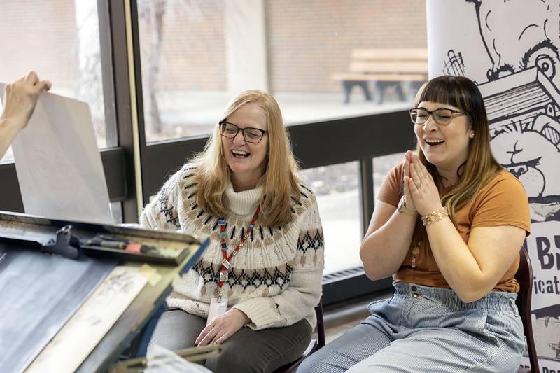 SVCC advisors Valerie Kern-Lyons (left) and Stephanie Jacobs react to seeing their caricature from artist Kevin Berg Tuesday, Jan. 17, 2023 at Sauk Valley College. The theme for their sketch was centered around their premier podcast which will drop sometime this week titled “Let’s Talk Sauk.”