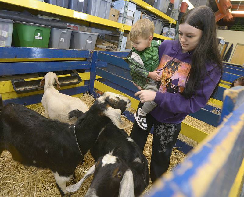 Ava Fortson holds Tatum Cosby in order to meet some goats during the Farm Fair organized by the Streator High School FFA Monday at the high school AG Shop.