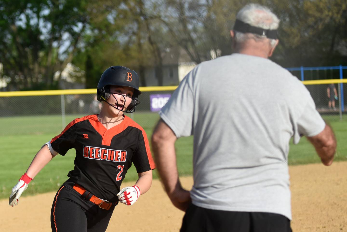 Beecher's Makenzie Johnson, left, greets coach Kevin Hayhurst as she rounds third base following a home run during a game at Wilmington Thursday, April 23, 2026.