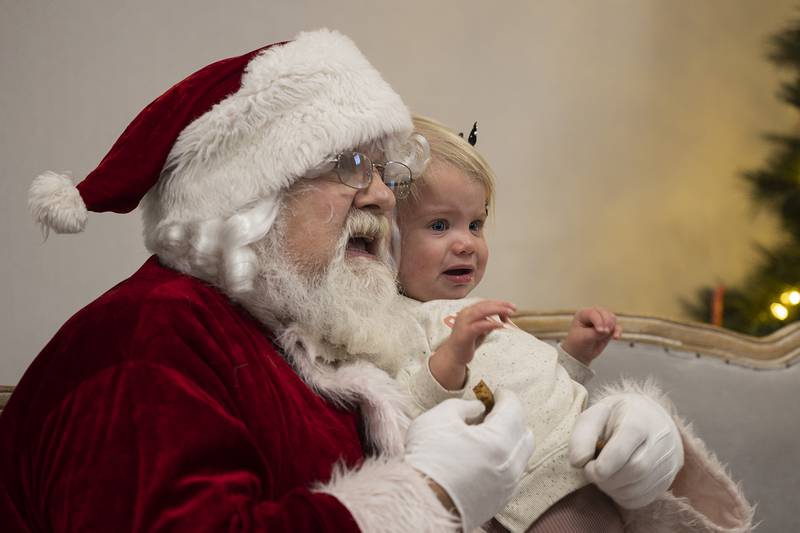 Bella Bennett, 1, of Dixon is still unsure about the red-draped Father Christmas Monday, Dec. 16, 2024, during Cookies with Santa at The Facility in Dixon.