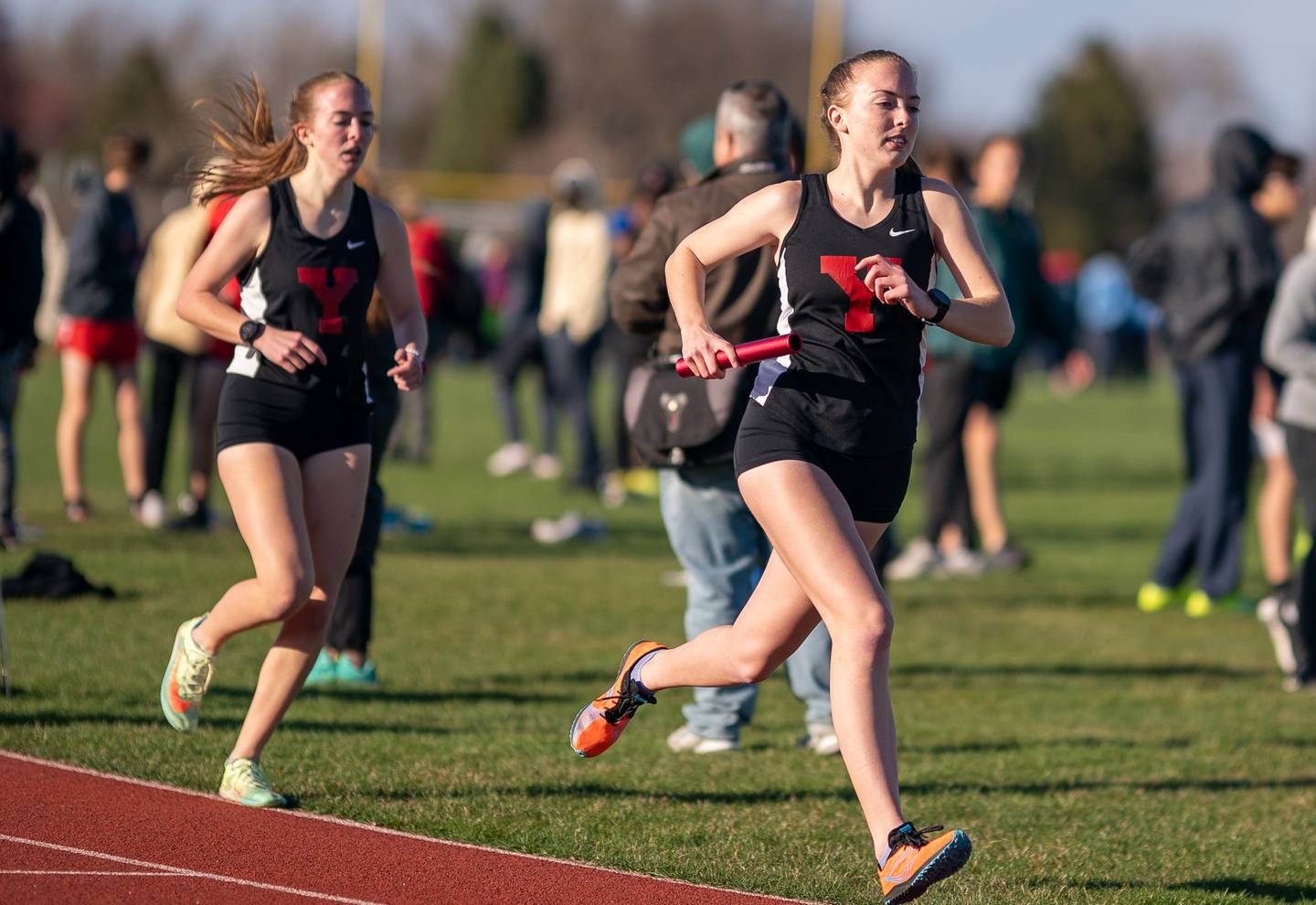 Yorkville’s Margaret Hunter (right) runs after receiving the relay baton from her sister Anna hunter in the 4 x 800 meter relay race during the Matt Wulf Invitational track and field meet at Yorkville High School on Thursday, April 14, 2022.