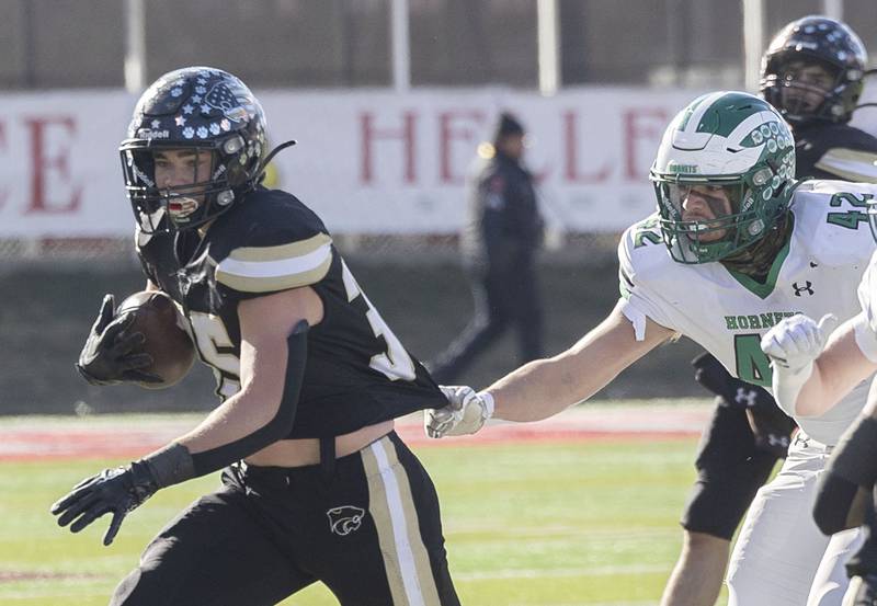 Lena-Winslow's Jaden Schubert looks for running room as Brown County's Micah Henry grabs his jersey Friday, Nov. 28, 2025, in the Class 1A football finals at Hancock Stadium at ISU.