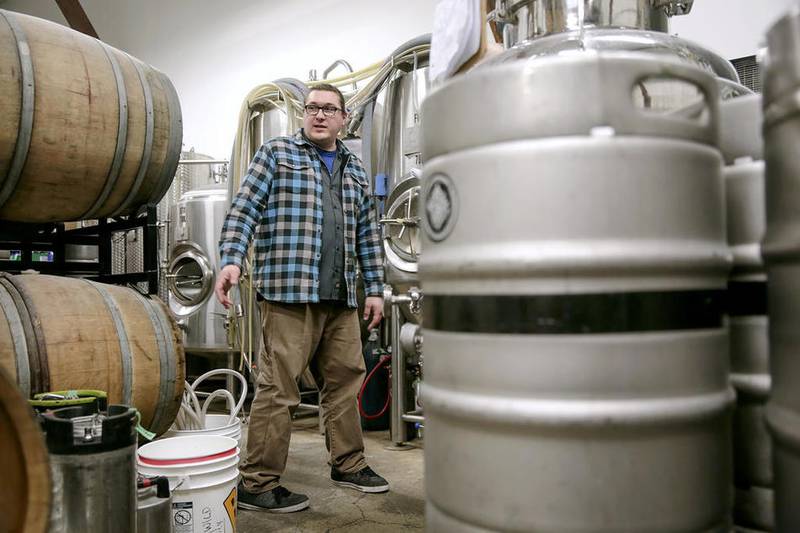 Brandon Wright, owner of Werk Force Brewing, stands between a series of fermenters and wooden barrels Monday at the brewery in Plainfield.