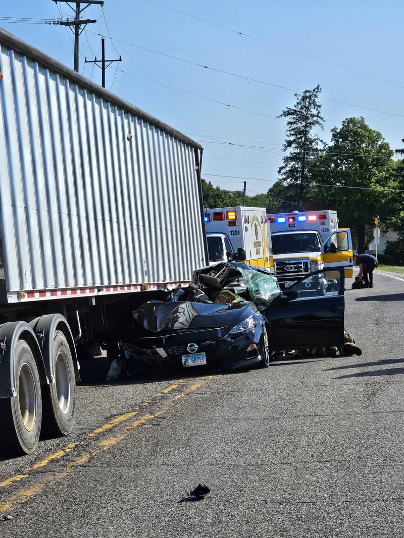 First responders aid two women in a sedan that drove under the rear tandem axles of a loaded semi-trailer Thursday, June 19 in Campton Hills.
