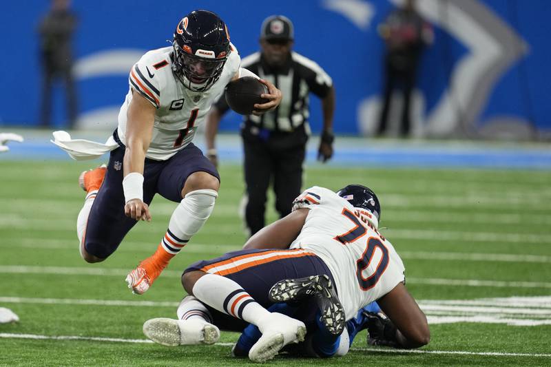 Chicago Bears quarterback Justin Fields jumps over a teammate as he scrambles during the first half against the Detroit Lions, Sunday, Jan. 1, 2023, in Detroit.